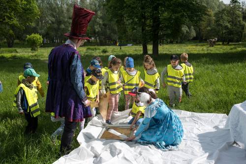 Zdjęcie przedstawia wydarzenie zorganizowane z okazji Dnia Dziecka w 2021 roku. Na zdjęciu widać animatorów oraz dzieci w parku w centrum miasta Pruszcz Gdański.